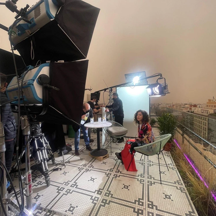 Glassy Films interview set on a city rooftop under a hazy orange sky, with lights and camera