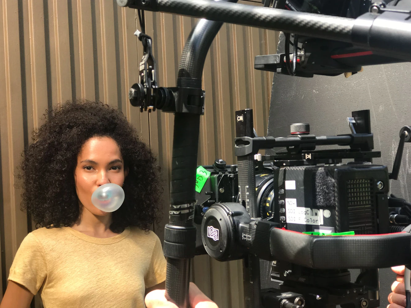 Actress blowing a bubblegum bubble next to a gimbal camera rig on a Glassy Films set