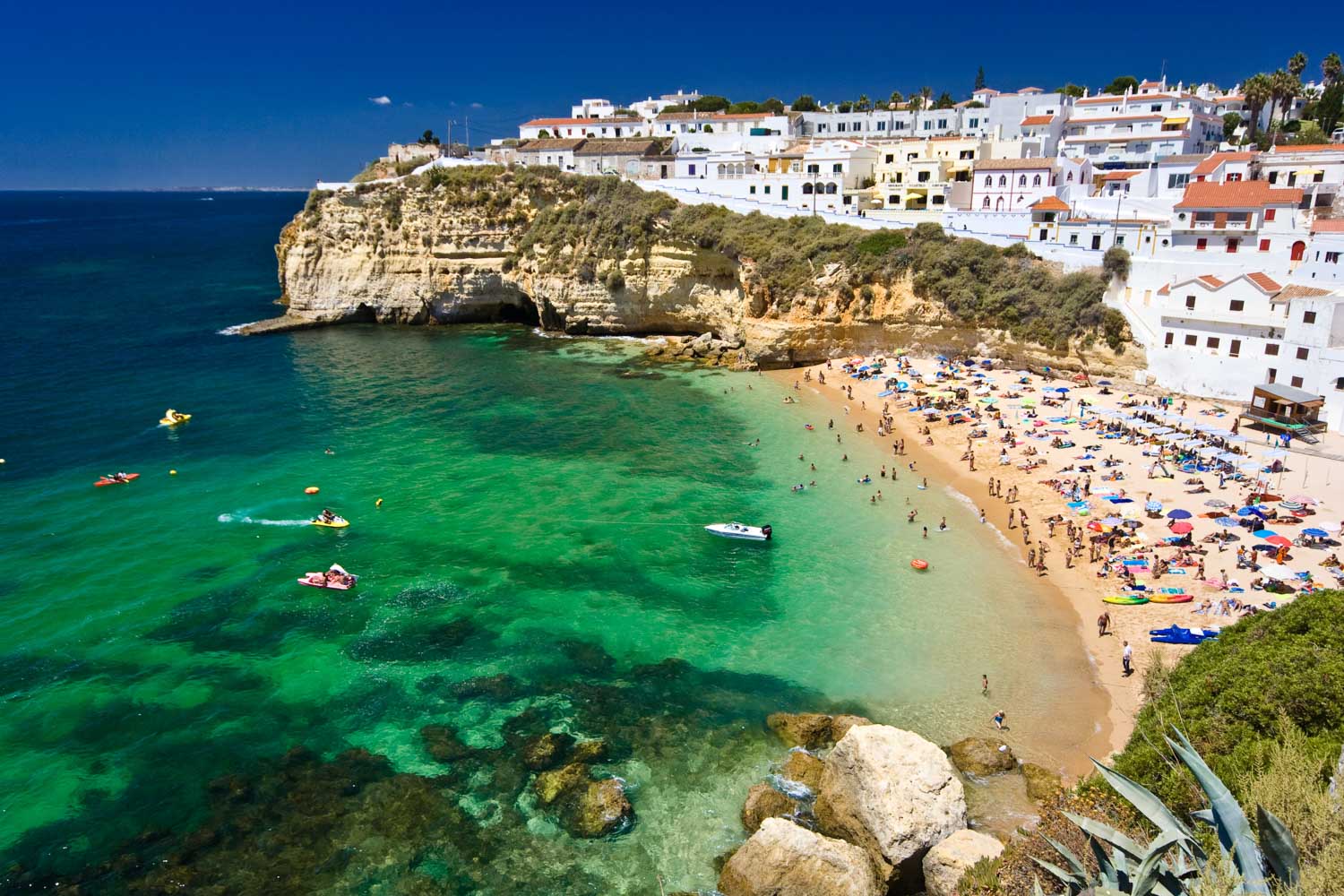 Turquoise cove beach below a white clifftop village