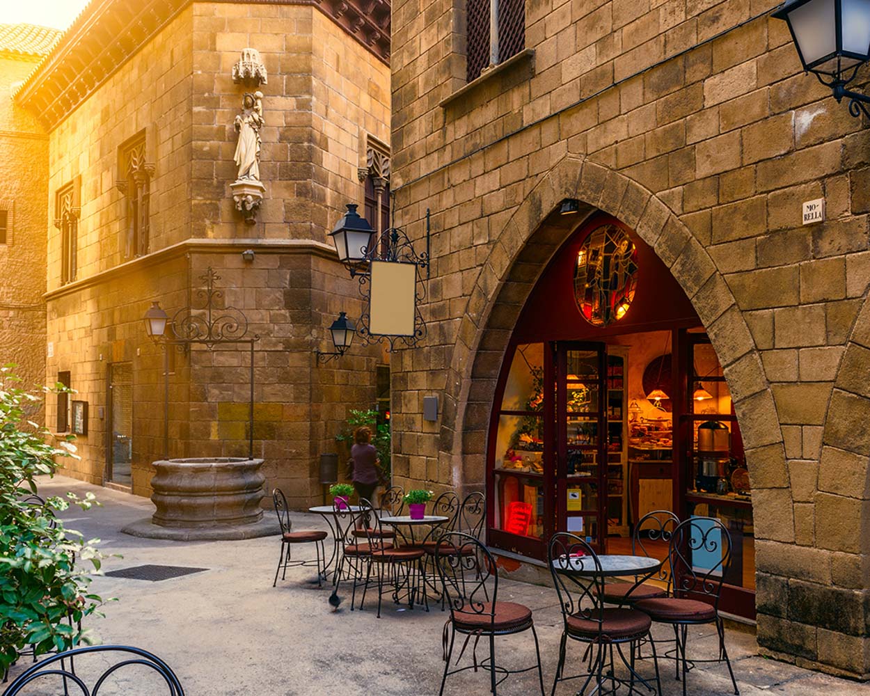 Stone square with a café under a Gothic arch at golden hour