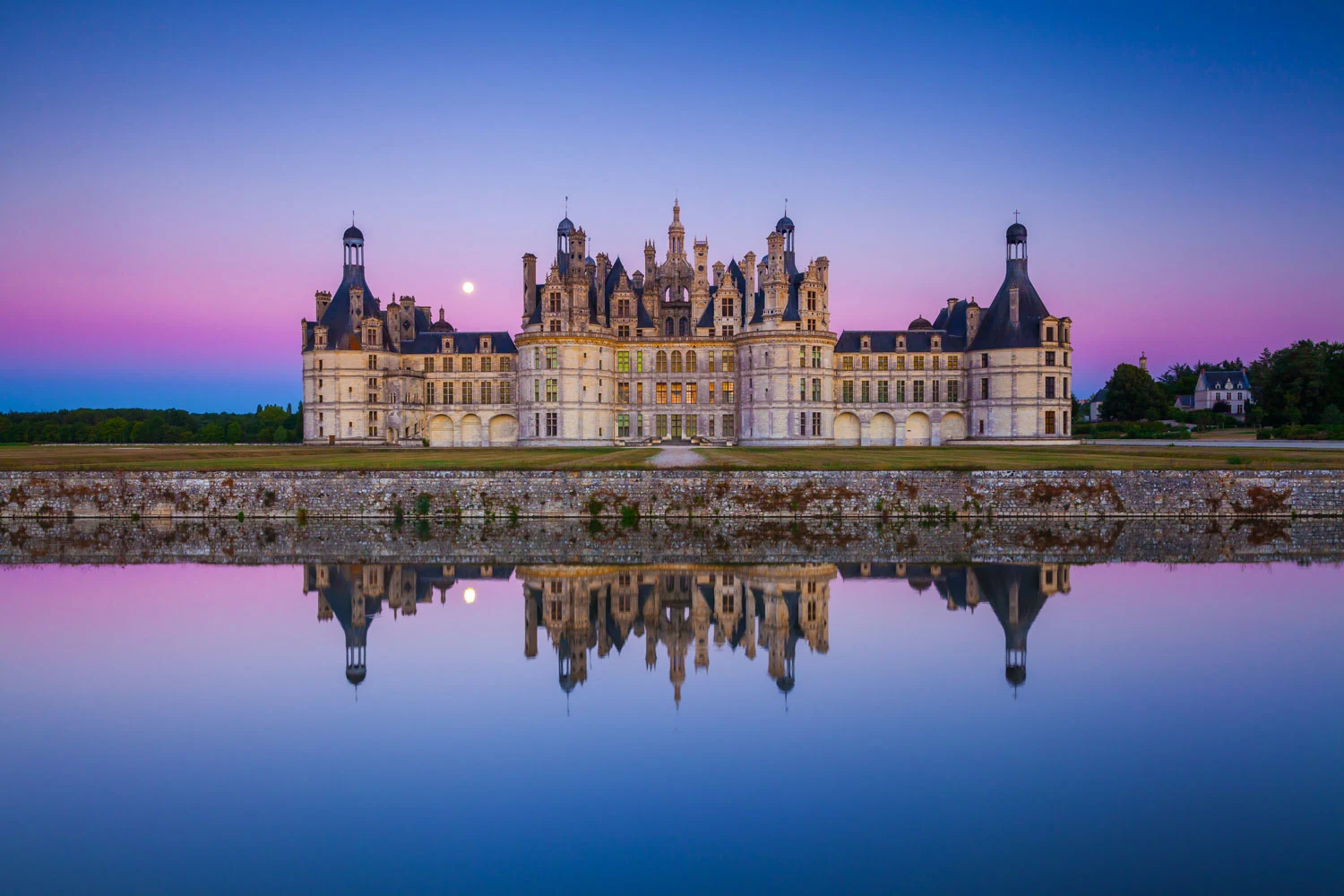 Renaissance château reflected in still water at twilight