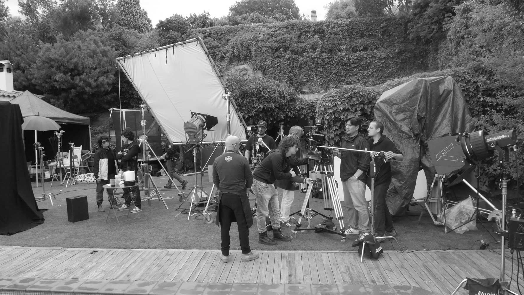 Black-and-white photo of a Glassy Films crew around the camera on an outdoor set