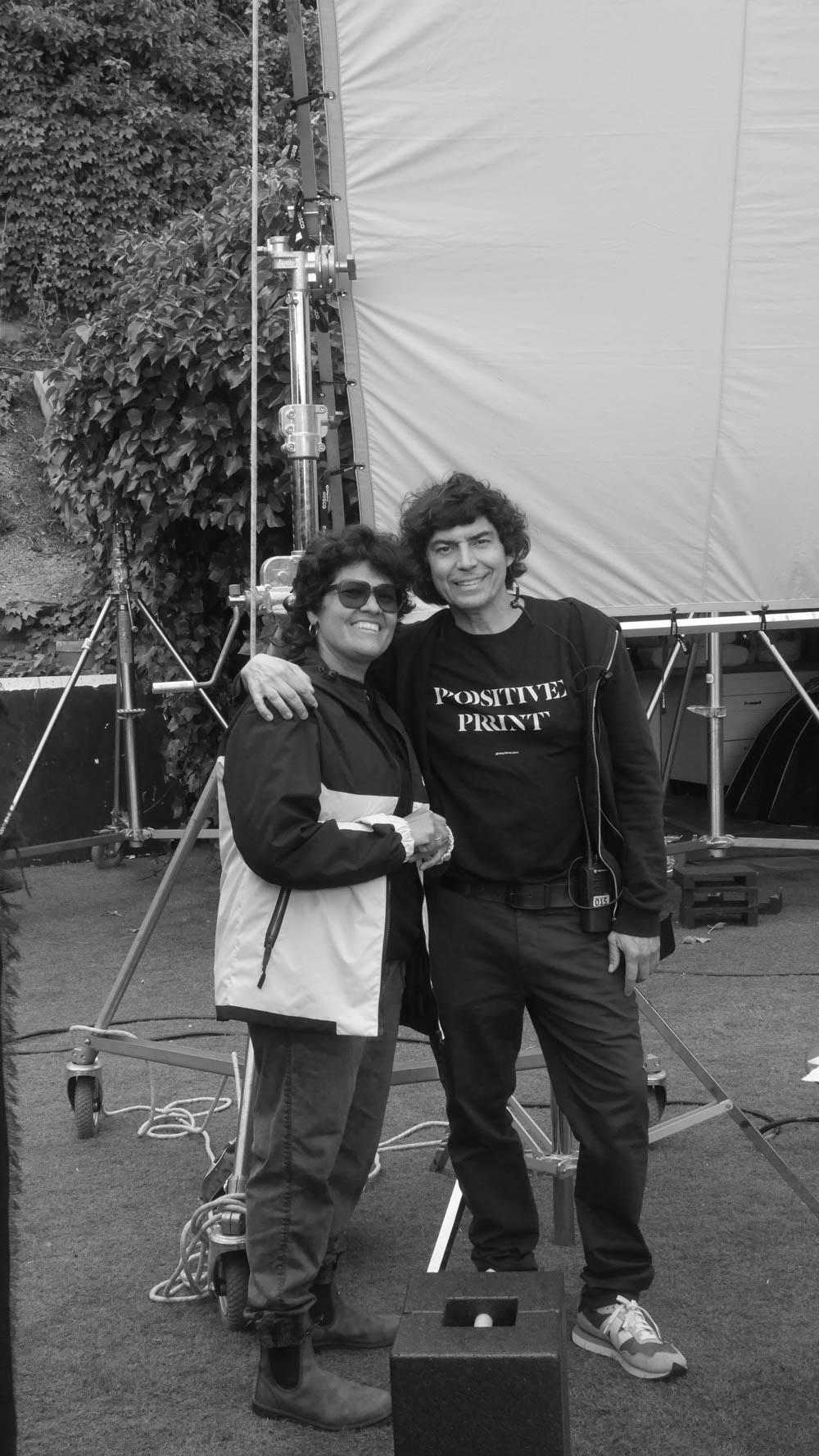 Two Glassy Films crew members posing on set in front of a large diffusion frame