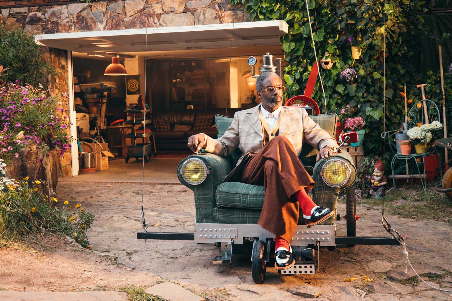 Man in a retro suit sitting in an armchair car outside a garage, on a Glassy Films shoot
