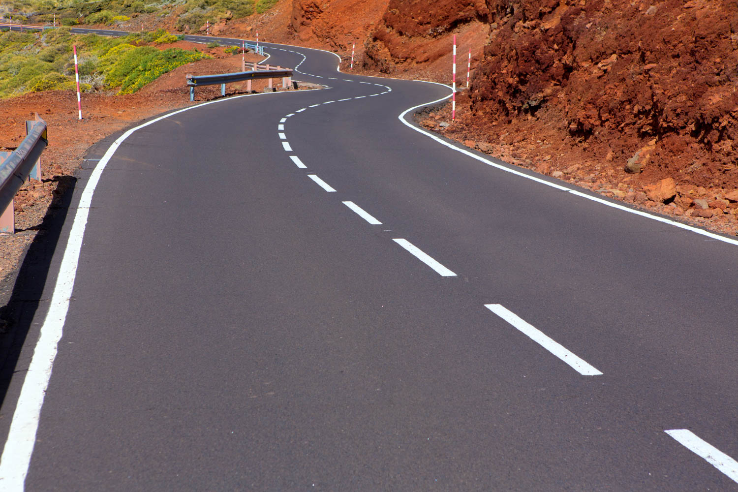 Winding mountain road between red volcanic slopes
